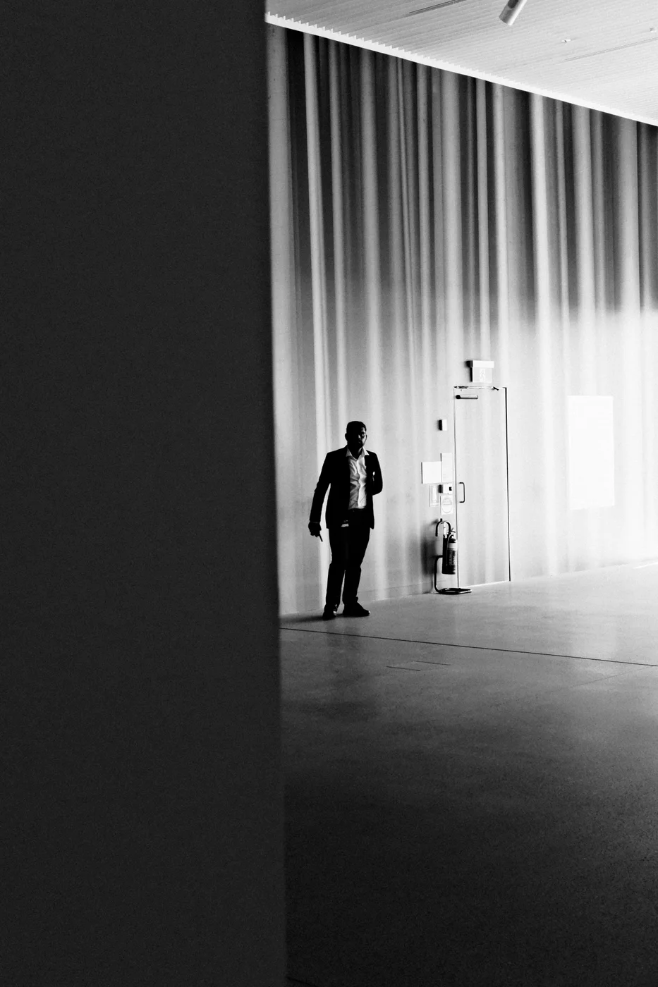 A visitor standing in a gallery beneath a tall wall of light