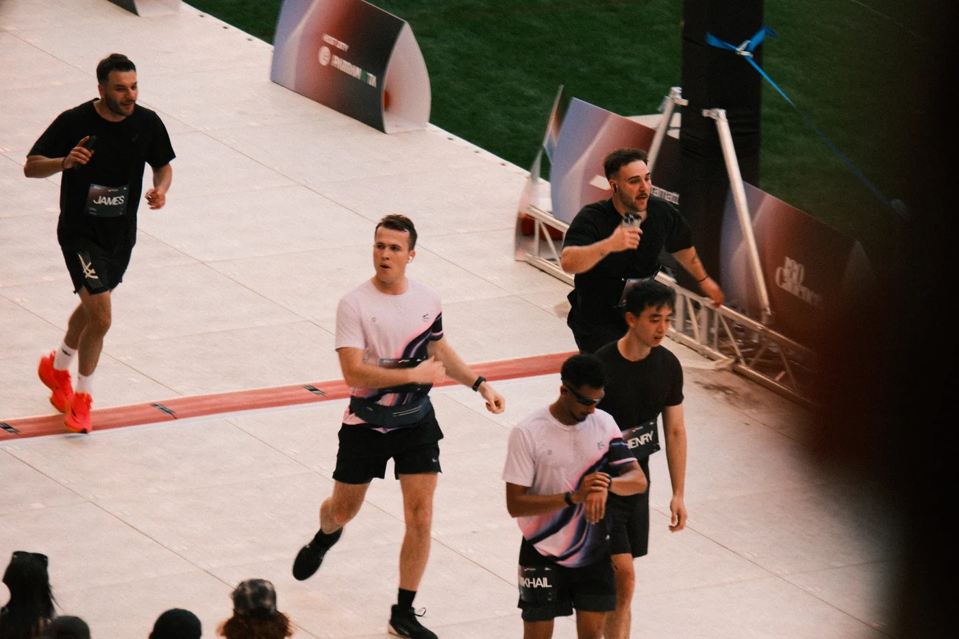 First race frame: the central runner’s forearm crosses the bib while their legs separate in stride